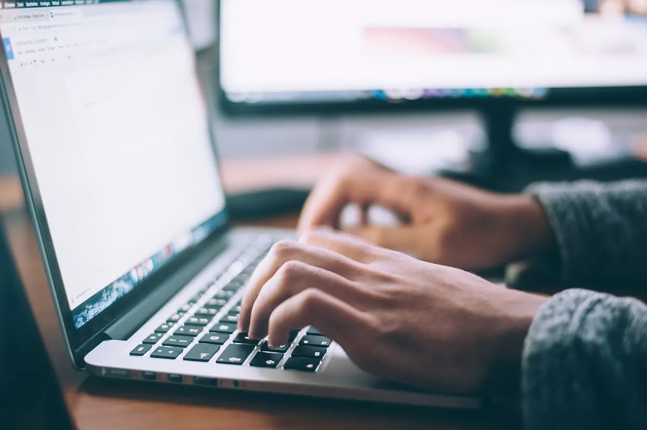 Hands typing on a laptop keyboard at a desk