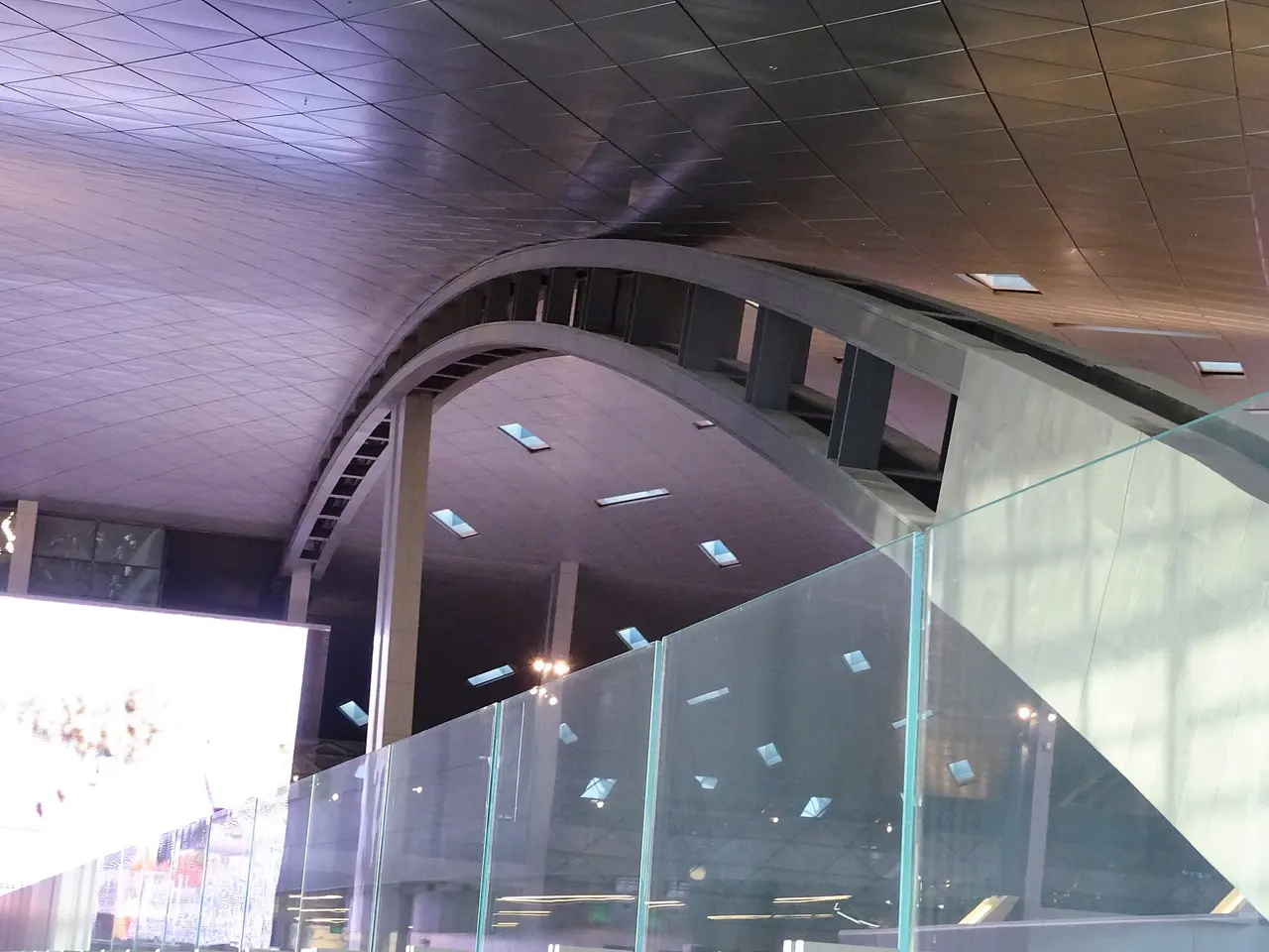 The curved ceiling and glass balustrade inside Hamad International Airport, Doha