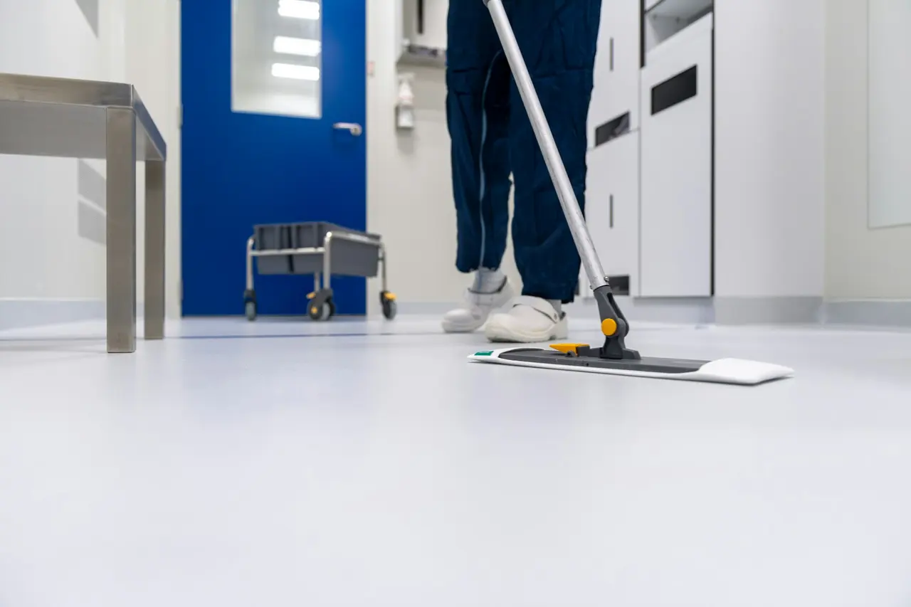 A cleaner mopping a clean white floor in a corridor