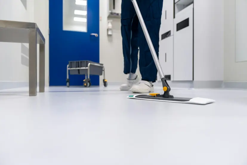 A cleaner mopping a clean white floor in a corridor