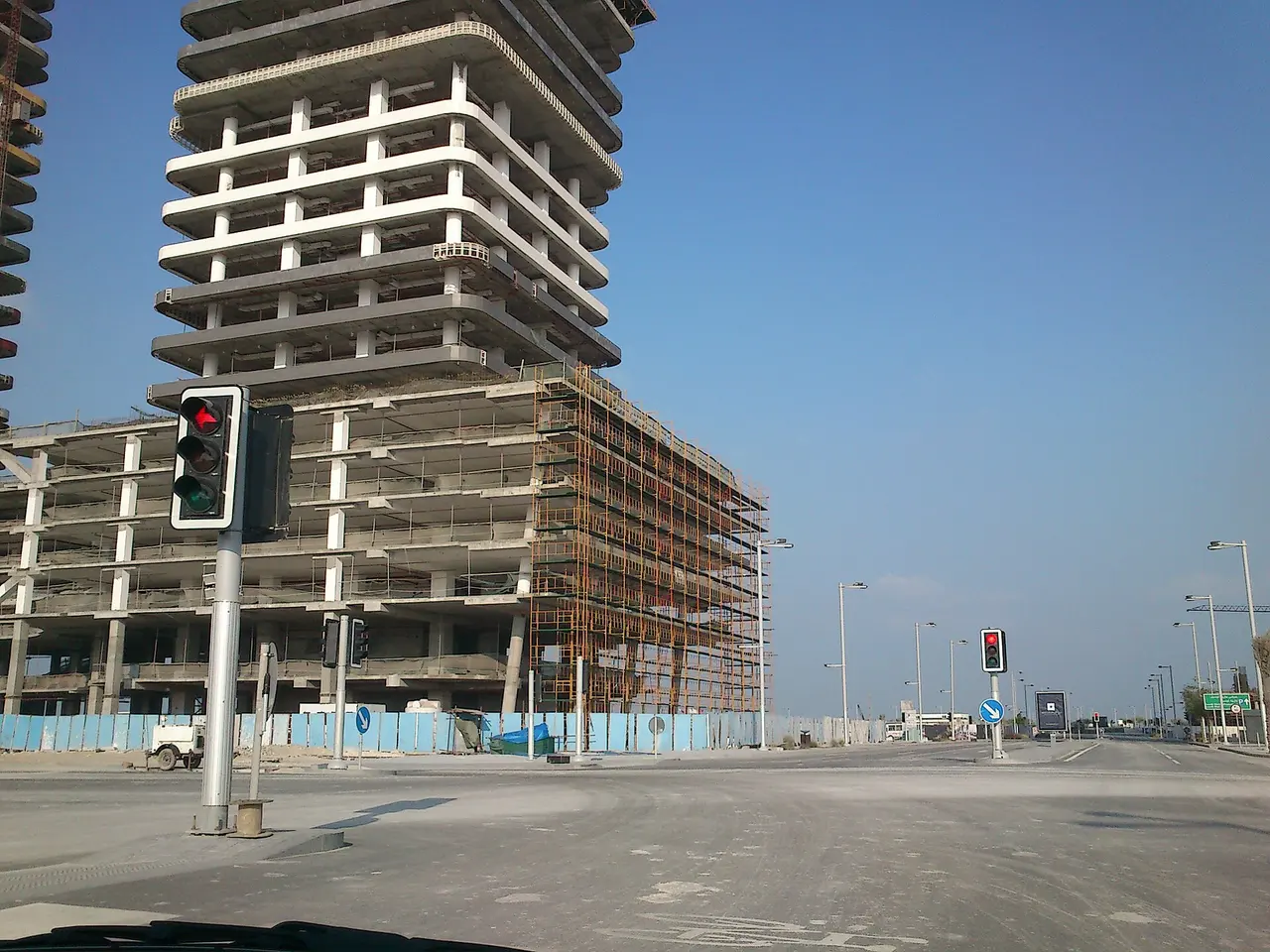 A tower under construction with scaffolding beside a road in Lusail