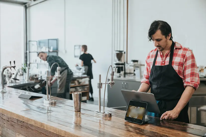 A café worker entering an order on a tablet till at the counter