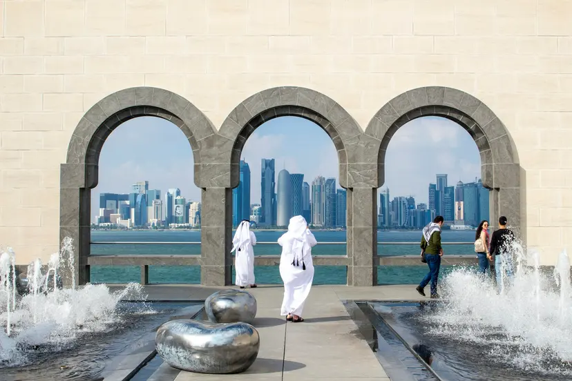 Visitors at the arches of MIA Park with the Doha skyline behind