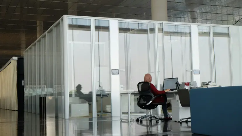 A person working at a desk in a glass study room in a Doha library