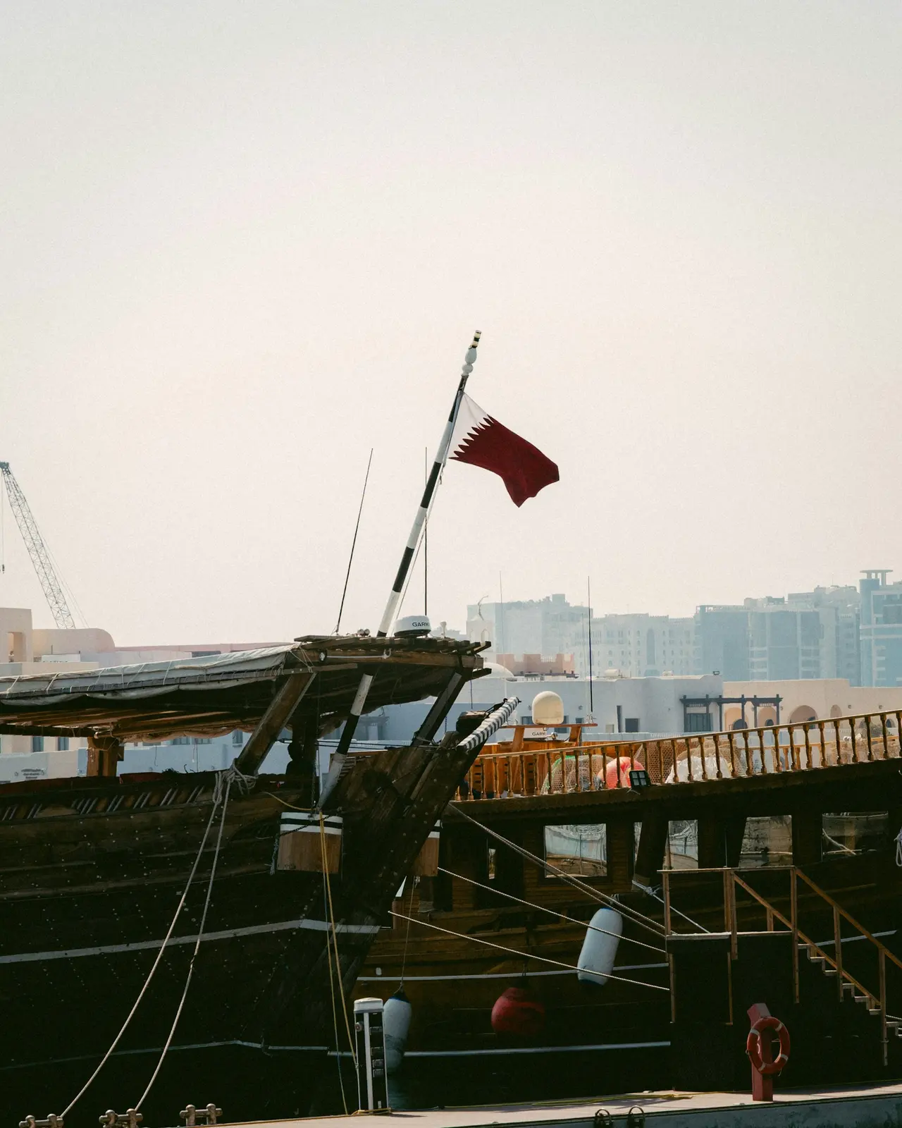 A wooden dhow flying the Qatar flag, moored in Doha harbour