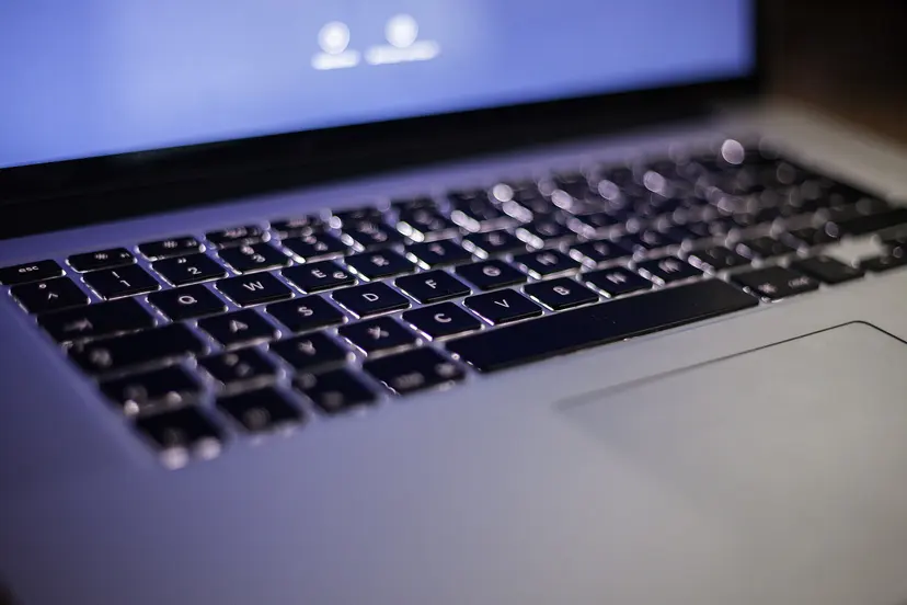 A backlit laptop keyboard in a dim room