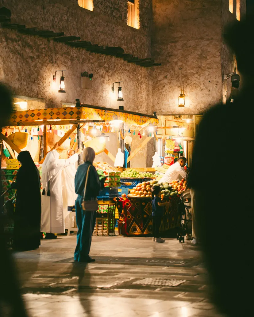 Shoppers at small fruit and produce stalls in a Doha market at night