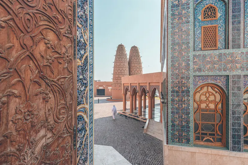 A carved wooden door and blue tiles framing the pigeon towers of Katara Cultural Village