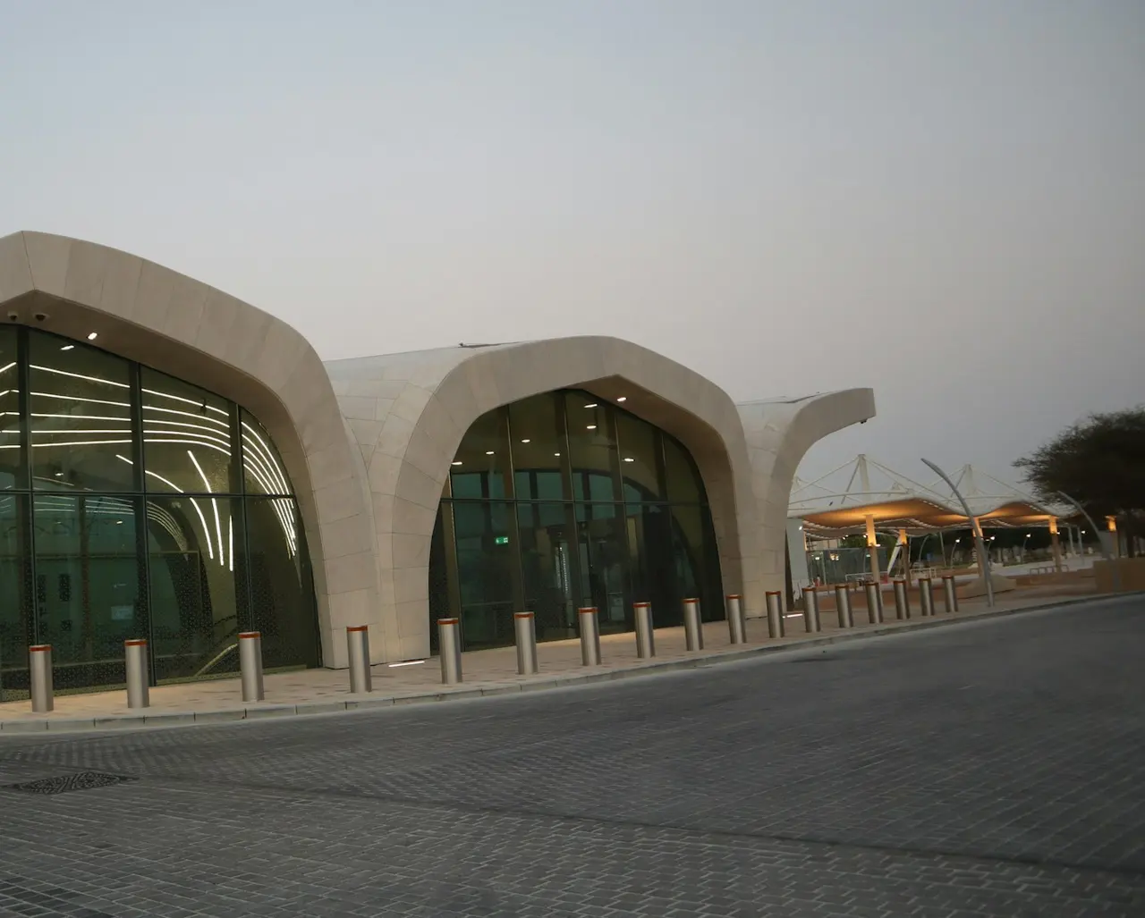 A Doha Metro station entrance with a curved stone roof and a glass front