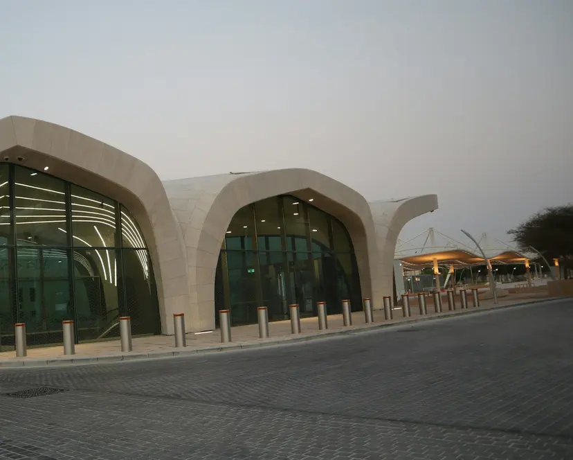A Doha Metro station entrance with a curved stone roof and a glass front