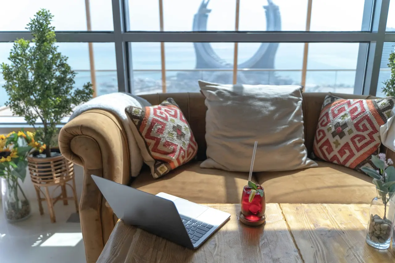 A laptop on a sofa by a window overlooking the Lusail coast in Qatar