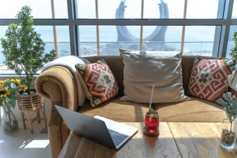 A laptop on a sofa by a window overlooking the Lusail coast in Qatar
