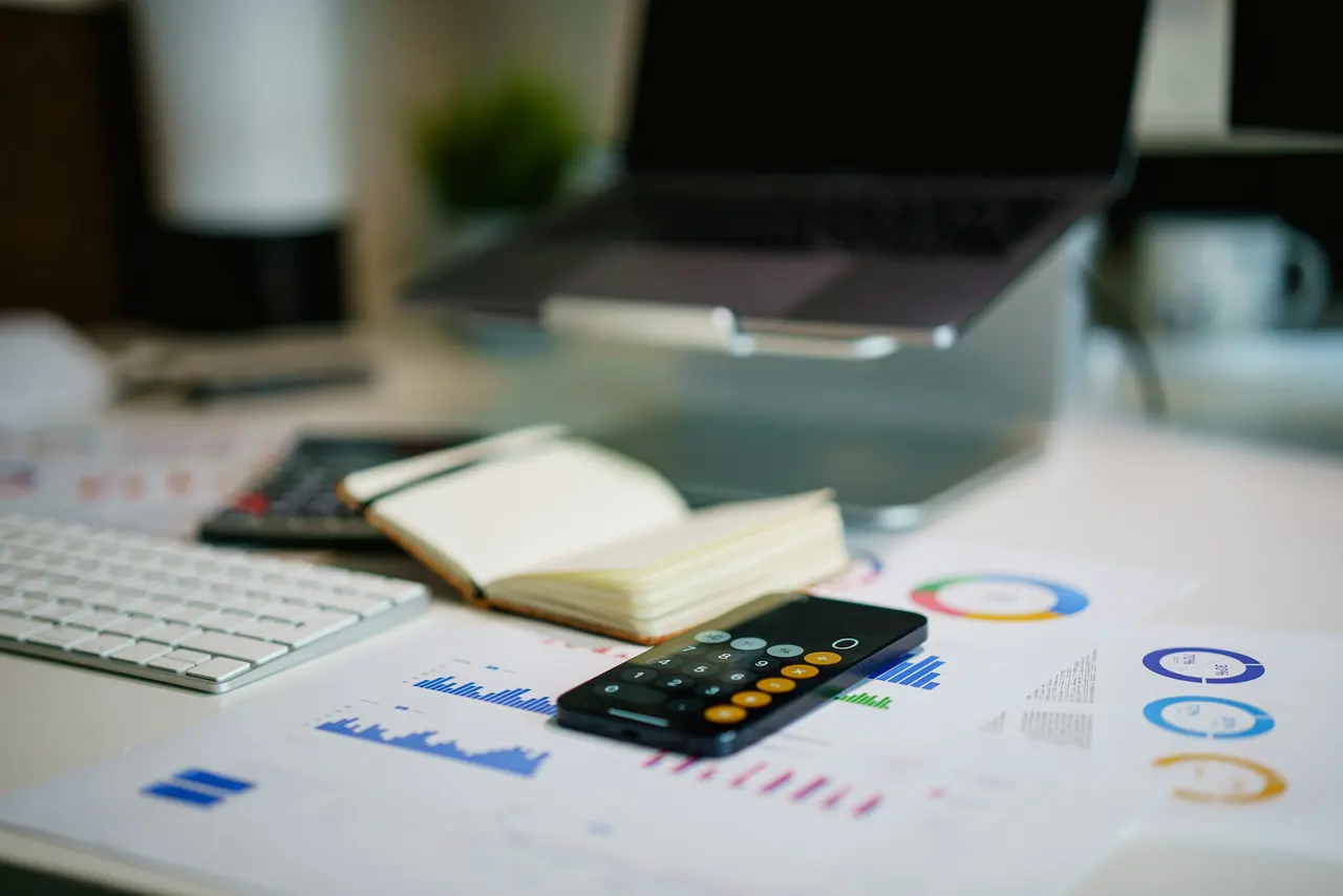 Financial charts, a calculator and a notebook on an office desk