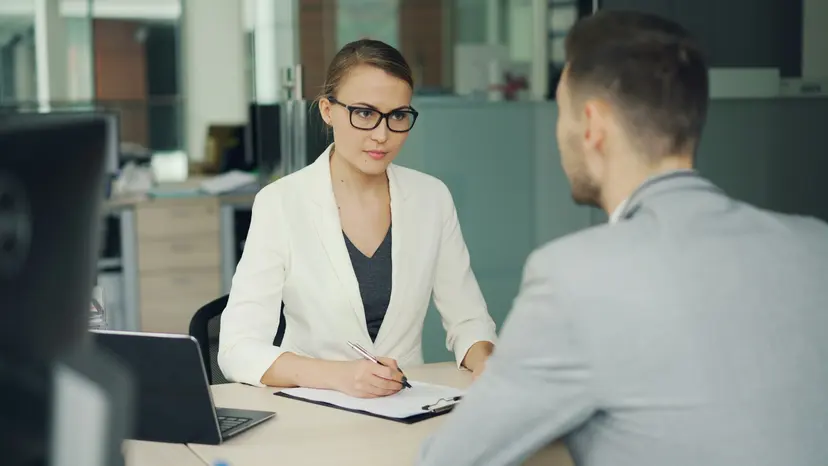 A manager taking notes while she interviews a job candidate across her desk