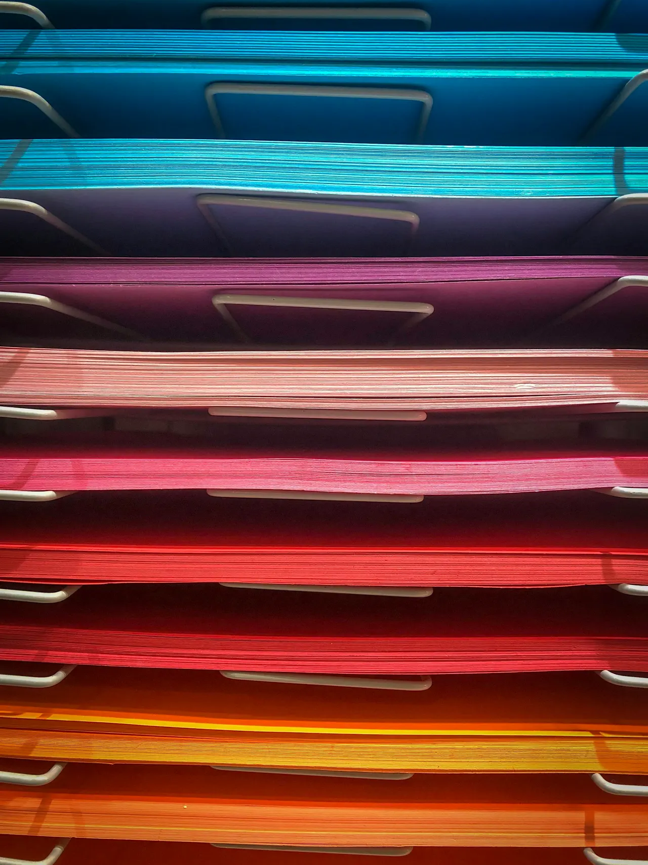 Stacked paper trays filled with coloured sheets