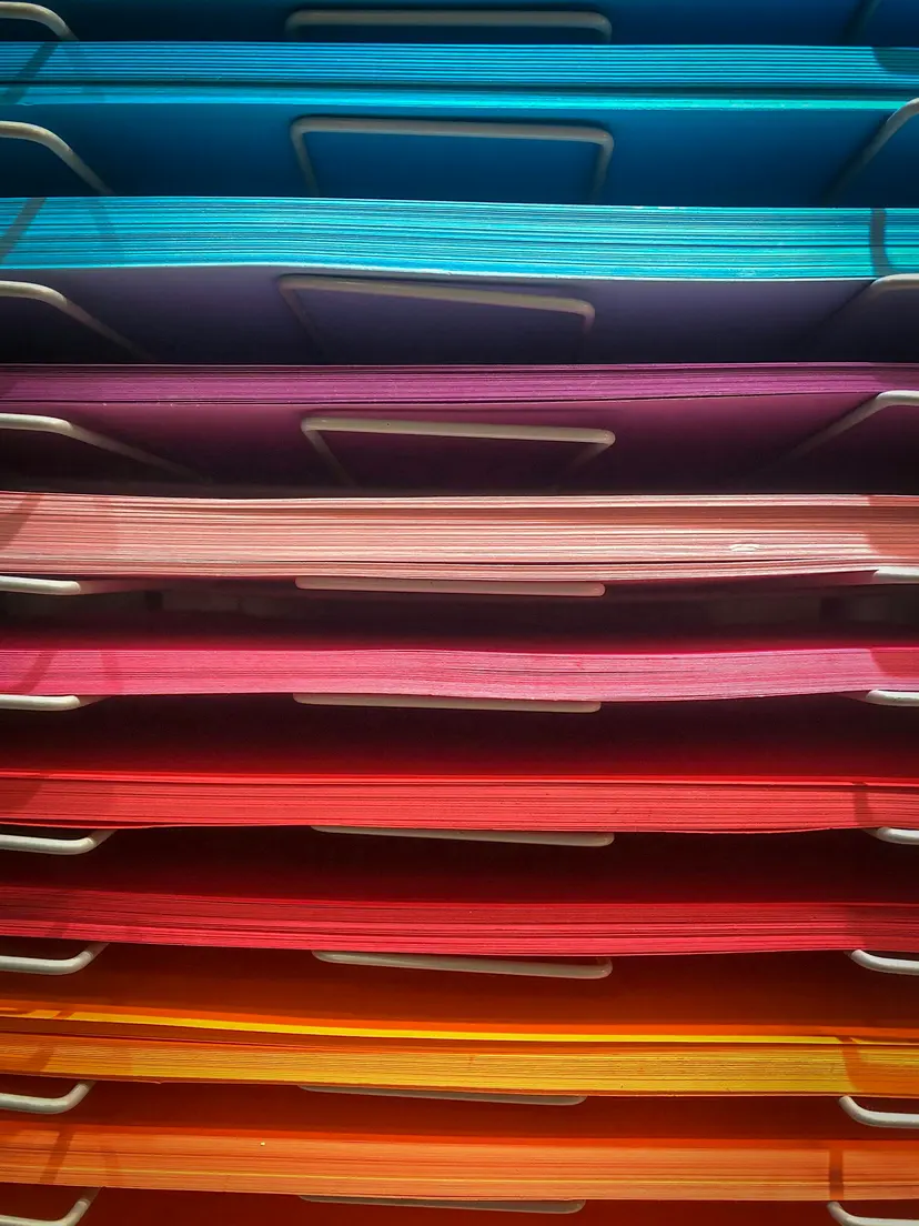 Stacked paper trays filled with coloured sheets