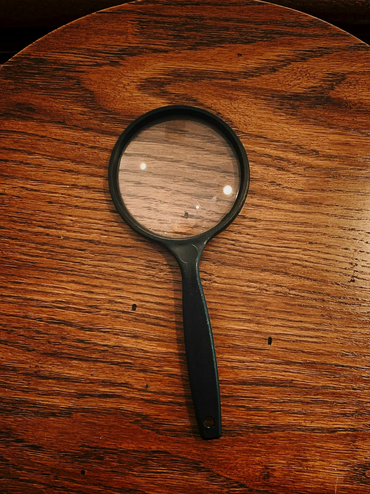 A magnifying glass lying on a wooden desk
