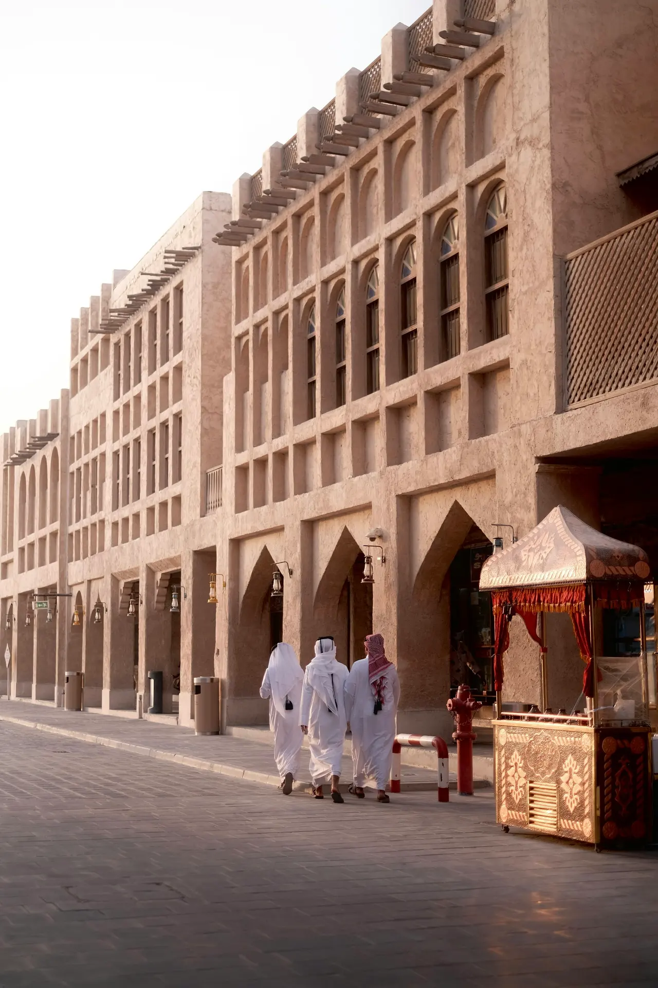 Men in traditional dress walking past shops in Souq Waqif, Doha
