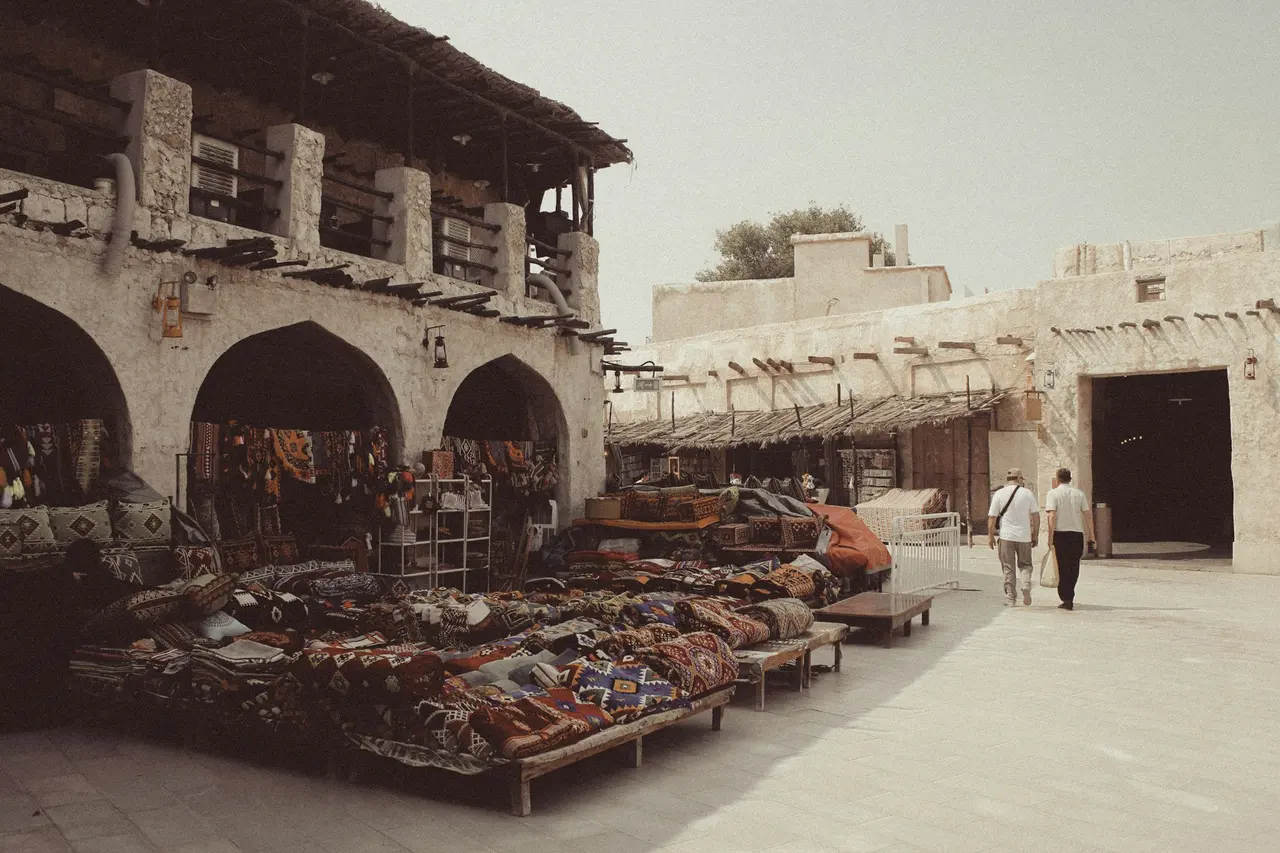 Shoppers walking past rug stalls in Souq Waqif, Doha