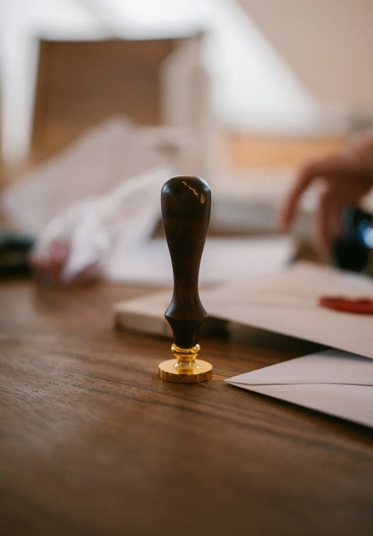 A wooden seal stamp beside an envelope on an office desk