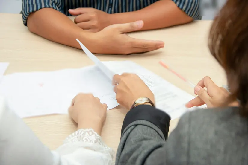 Two people going through job application papers across a table