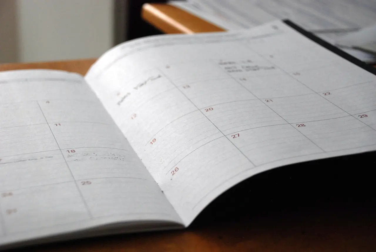 An open monthly planner with dates marked, on a desk
