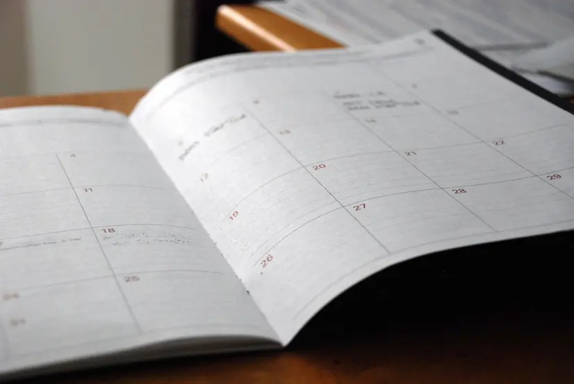 An open monthly planner with dates marked, on a desk