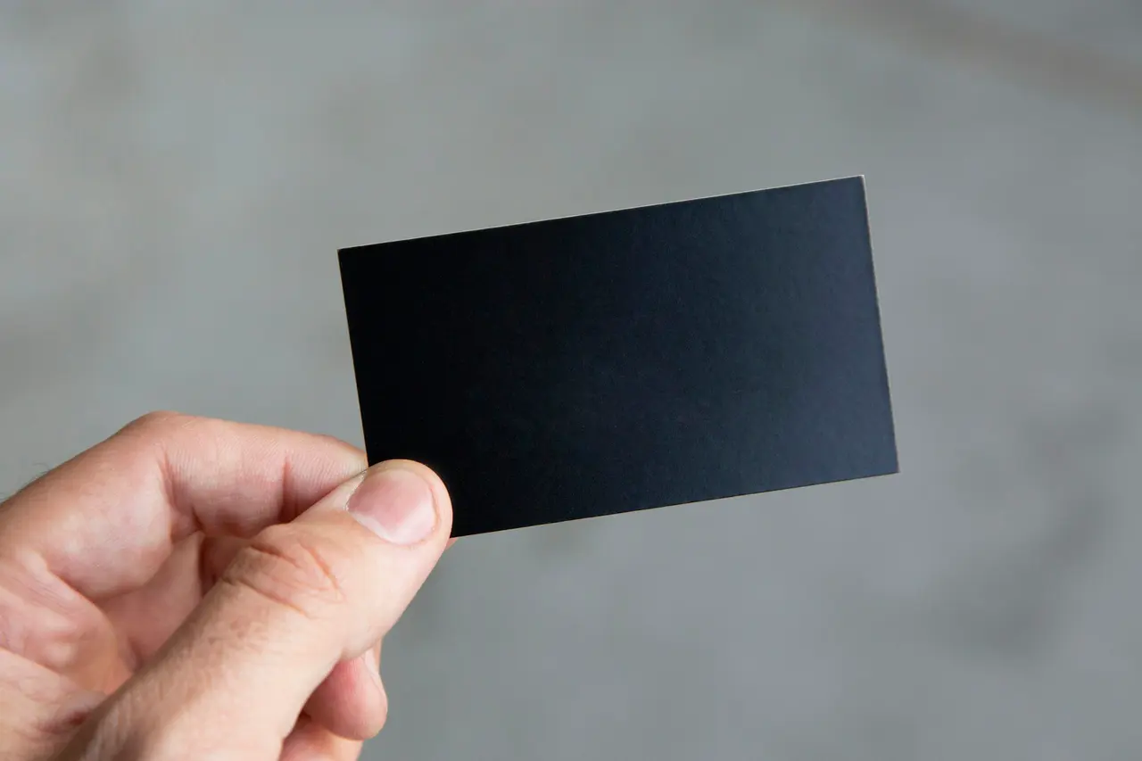 A hand holding a plain black card