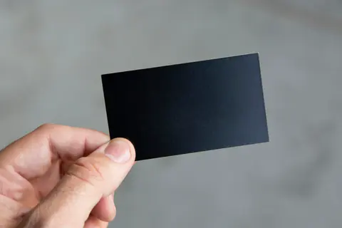 A hand holding a plain black card