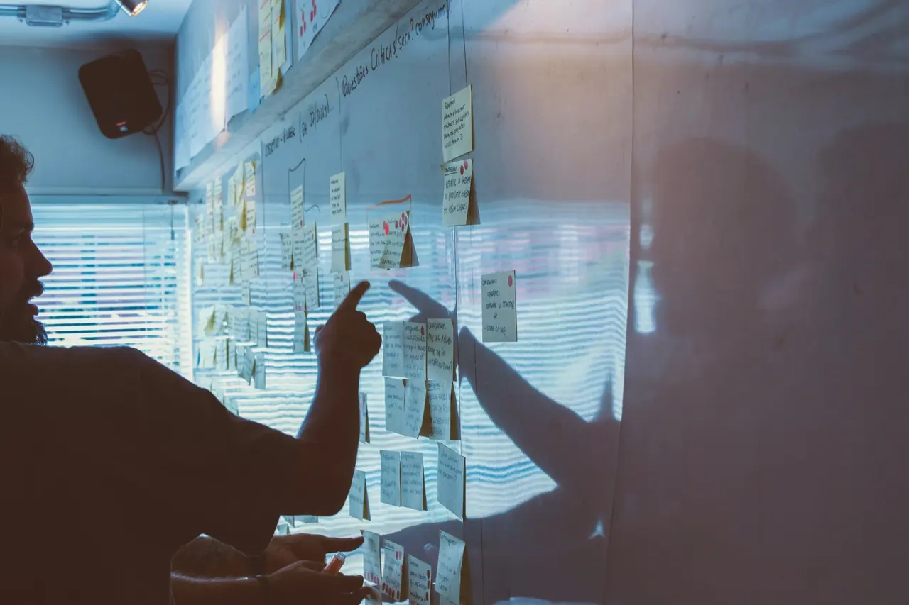 A team pointing at plans and notes on a strategy wall